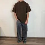 Remera de corte oversize en color verde oliva con efecto lavado, confeccionada en tela rústica pesada, con cuello redondo y bordes sin costura.