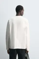 Camiseta de manga larga con corte relajado, confeccionada en tejido compacto de algodón. Presenta cuello redondo acabado en rib y detalle de costura central en la espalda.