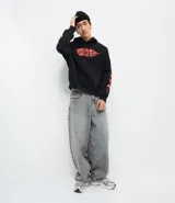 Buzo con capucha negro de corte oversized, con bolsillo canguro y cordones ajustables. Presenta un estampado frontal con una calavera y la palabra 'FEARLESS' envuelta en llamas naranjas y rojas, diseño que se repite en las mangas.