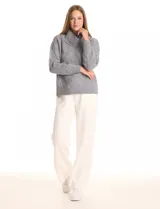 Buzo de punto grueso con textura en relieve, de cuello volcado y mangas largas con hombros caídos. Presenta puños y ruedo con terminación en rib.