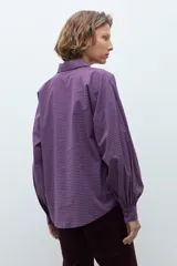 Camisa de manga larga con estampado de cuadros pequeños en tonos violeta y rojo, con cuello clásico y cierre frontal de botones.