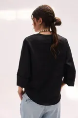 Blusa de lino color lila, de corte relajado y mangas largas amplias, con escote en V y ruedo curvo.