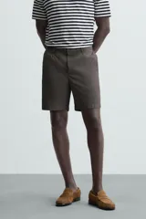 Bermuda de hombre color beige claro, corte regular fit, con pliegues frontales, bolsillos delanteros y bolsillos traseros de doble vivo con botón.