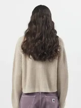 Sweater de punto acanalado color negro, con cuello redondo, mangas largas y un bolsillo frontal en el pecho con etiqueta de la marca.