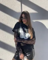 Remera negra de algodón con estampa frontal gráfica, combinada con mangas largas de encaje negro incorporadas.