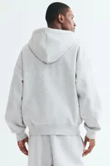 Campera con capucha y cierre frontal de H&M, color gris melange, con hombros caídos, bolsillos tipo canguro y ajuste oversized.