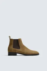 Bota estilo Chelsea fabricada en piel con acabado de serraje, cuenta con elásticos laterales para facilitar el calce, horma redonda y suela a contraste con un ligero tacón.
