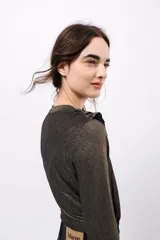 Remera de manga larga confeccionada en tejido de lurex negro con destellos dorados. Detalle de volados en el cuello tipo collar.