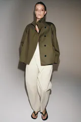 Pantalón de tiro medio confeccionado en mezcla de algodón, con diseño cruzado frontal y cierre de botones. Presenta cintura con trabillas, bolsillos laterales ocultos y detalle de bolsillo con solapa y botón en el delantero.