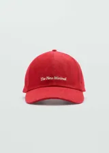 Gorra de béisbol color rojo, confeccionada en algodón con textura tipo denim. Presenta un mensaje bordado en el frente y cierre metálico ajustable en la parte posterior.