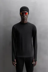 Camiseta negra de running de primera capa, confeccionada en tejido elástico y ajustado al cuerpo. Tiene cuello alto con logo estampado, mangas largas con puños ajustables y costuras planas.