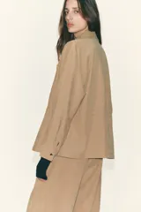 Chaqueta color tostado con cuello solapa, manga larga y cierre frontal con cremallera. Presenta bolsillos delanteros de plastrón con solapa y detalle de cintura ajustable con lazada.