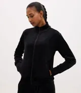 Campera deportiva de mujer confeccionada en tejido plush aterciopelado. Presenta cuello alto, cierre frontal con cremallera y puños ajustados.