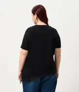 Blusa de manga corta con escote redondo, confeccionada en algodón. Presenta un diseño alargado con un detalle de encaje irregular aplicado en el ruedo, aportando un acabado asimétrico y delicado.