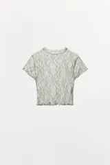 Top crop semitransparente de encaje negro, con cuello redondo y manga corta.