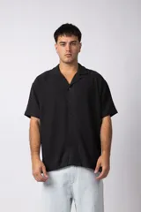 Camisa de manga corta con cuello cubano, confeccionada en lino entramado de textura natural. Presenta un corte relajado y cierre frontal con botones.