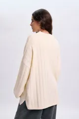 Sweater de punto liso en color crudo, de diseño oversize con cuello redondo acanalado y mangas amplias.