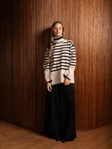 Poleron de punto con diseño a rayas horizontales en color beige y negro, cuello alto tipo tortuga, mangas largas con puños anchos y aberturas laterales en el ruedo.