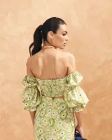 Blusa corta con estampado floral en tonos amarillo y verde, escote bardot, mangas abullonadas 3/4 con puños elásticos y espalda elastizada.