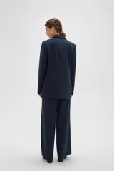 Blazer de corte holgado con diseño de rayas verticales, cuello solapa y cierre frontal con un botón. Presenta bolsillos laterales con solapa y mangas largas.