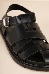 Sandalias bajas tipo gladiador, color negro, con tiras entrelazadas y hebilla metálica ajustable.
