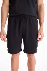 Bermuda tipo cargo confeccionada en felpa sin friza, de color negro, con bolsillos laterales y cintura elástica con cordón ajustable.