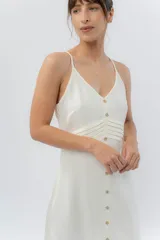 Vestido midi celeste de tejido tipo seda fría, con breteles finos regulables, botones de madera decorativos en el frente, pliegues decorativos en la cintura y cierre invisible en el costado.