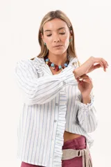 Camisa de manga larga con diseño a rayas celestes y blancas, cuello alto y detalle de volados en la cartera frontal y los puños.