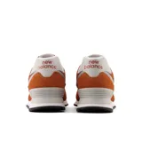 Championes New Balance 574 color naranja con detalles en blanco, confeccionados en gamuza y malla, con logo "N" característico en los laterales y entresuela ENCAP.