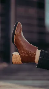 Botineta de cuero marrón con taco ancho efecto madera, plataforma sutil y detalles de elástico texturizado en los laterales.