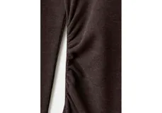 Vestido largo de corte ajustado en color marrón oscuro, con escote bote y mangas largas. Presenta un diseño minimalista con un sutil fruncido lateral en la cintura que realza la silueta.