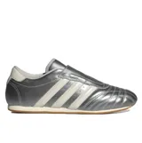 Championes Adidas modelo Taekwondo, color plateado metalizado con las tres tiras características en blanco. Presentan un diseño de perfil bajo, sin cordones visibles y suela de goma fina.