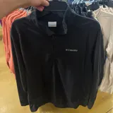 Buzo de polar Columbia, color negro, con cuello alto y cierre frontal parcial. Presenta el logo de la marca bordado en el pecho.