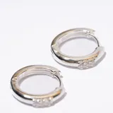 Aros tipo argolla plateados con pequeños brillantes incrustados.