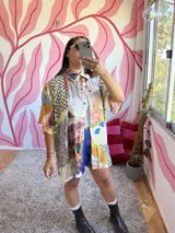 Camisa oversize de seda con estampado patchwork que combina diferentes patrones como cuadros, animal print, rayas y motivos florales. Tiene cuello camisero, botones frontales y mangas cortas.