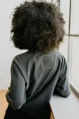 Buzo de manga larga color gris oscuro/negro desteñido, con cuello redondo y puños y ruedo acanalados. Estampado frontal con el logo de The Rolling Stones (lengua y labios) en dorado y texto en cursiva.