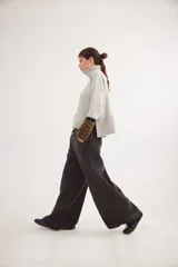 Pantalón sastrero de tiro medio confeccionado en pana de algodón, con corte amplio y diseño bicolor en los laterales. Cuenta con bolsillos delanteros y traseros, y un detalle de aplique con ojalillo en la parte inferior de una de las piernas.