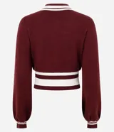 Cardigan de punto estilo college color bordó, con cierre frontal de doble cremallera, mangas largas y detalles de rayas blancas en cuello, puños y ruedo. Presenta una estampa numérica blanca en el frente.