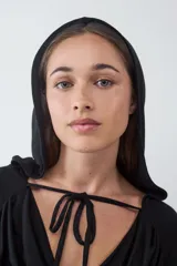 Top de manga larga color negro, con escote drapeado y detalle de tiras finas para anudar en el cuello. Confeccionado en tejido elástico y suave.