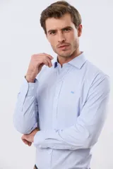 Camisa de vestir de manga larga con diseño de rayas finas celestes y blancas, cuello clásico y cierre frontal con botones. Incluye pequeño logo bordado en el pecho.