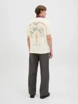 Remera color hueso de algodón con cuello redondo y manga corta. Estampado en la espalda con diseño de hojas de palmera y texto "Brezza Del Mattino Originals Summer Edition EST 1990".