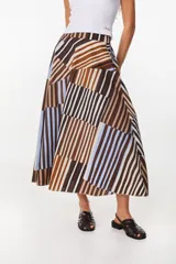 Falda midi de algodón, con diseño geométrico de paneles con rayas verticales en tonos marrón, celeste, blanco y negro. Presenta pretina elastizada en la parte trasera y silueta evasé.