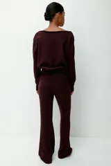 Buzo de punto fino color bordó, con escote off-the-shoulder y hombros caídos. Tiene mangas largas y remate acanalado en puños y bajo.