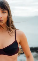 Top de bikini negro con borde bordeaux, con aro y breteles finos.