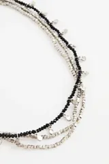 Collar de varias capas con cuentas negras y pequeñas piezas metálicas doradas en forma de disco, que aportan un estilo delicado y brillante.