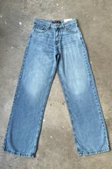 Jean de mezclilla celeste, corte holgado o recto, con grandes estrellas estampadas en color blanco o gris claro en los bolsillos traseros. Tiene un parche de cuero marrón en la cintura trasera con el logo de la marca.