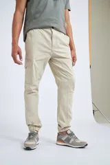 Pantalón cargo color beige con ajuste slim, cierre frontal con botón, bolsillos laterales tipo cargo y puños elásticos en los tobillos.