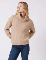 Buzo de punto grueso con textura en relieve, de cuello volcado y mangas largas con hombros caídos. Presenta puños y ruedo con terminación en rib.