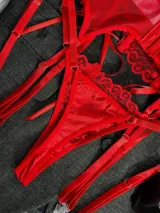 Conjunto de lencería rojo de encaje floral, compuesto por un corpiño tipo corset con aro y tirantes finos, una bombacha colaless regulable y ligas con cintas ajustables.