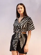 Camisa corta con estampado de cebra en blanco y negro, cuello camisero, escote en V y nudo frontal.